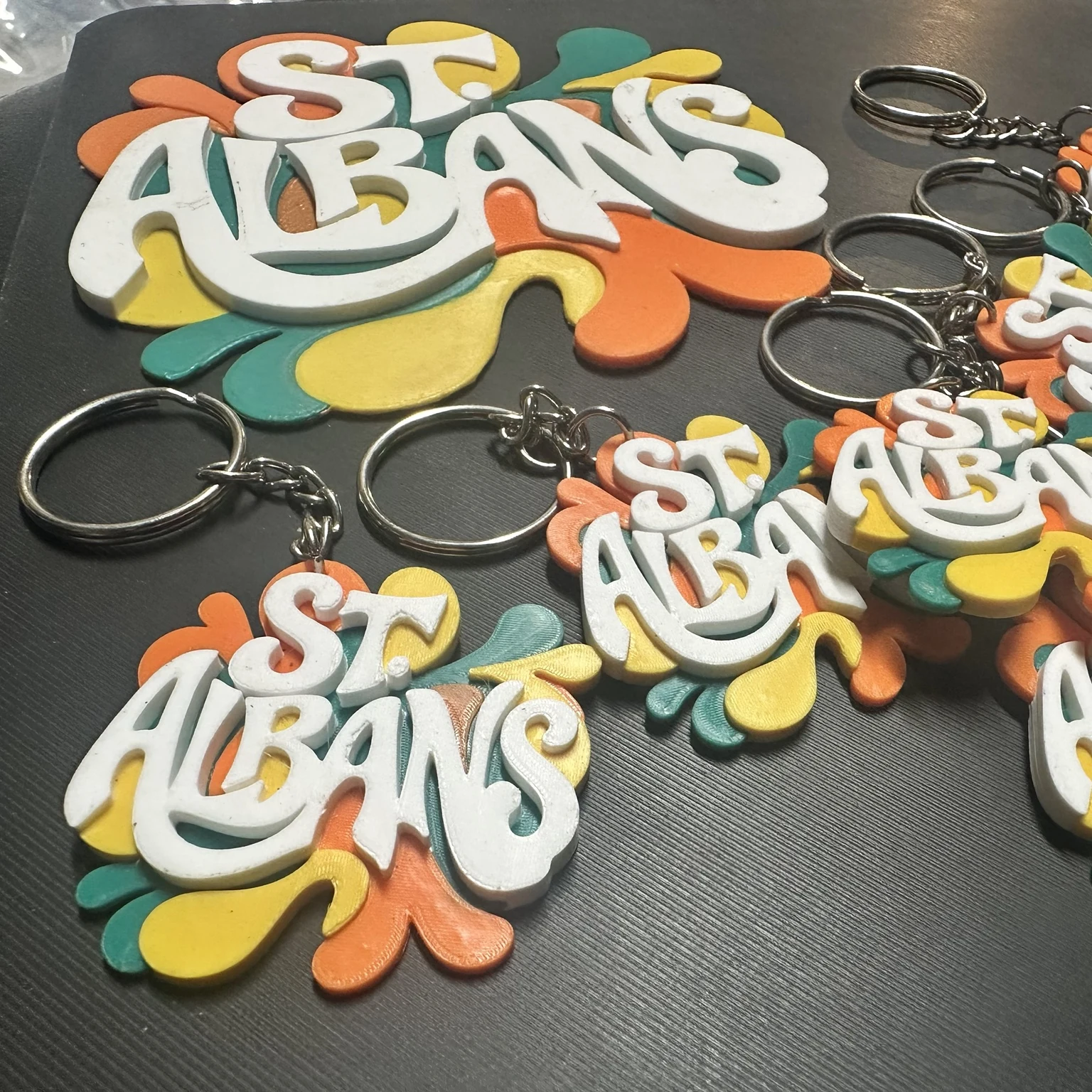 St. Albans keychains with metal rings beside a larger printed version of the design